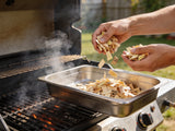 Western BBQ Products Apple Smoking Wood Chips lifestyle photo — loading apple wood chips into a smoker tray on the grill