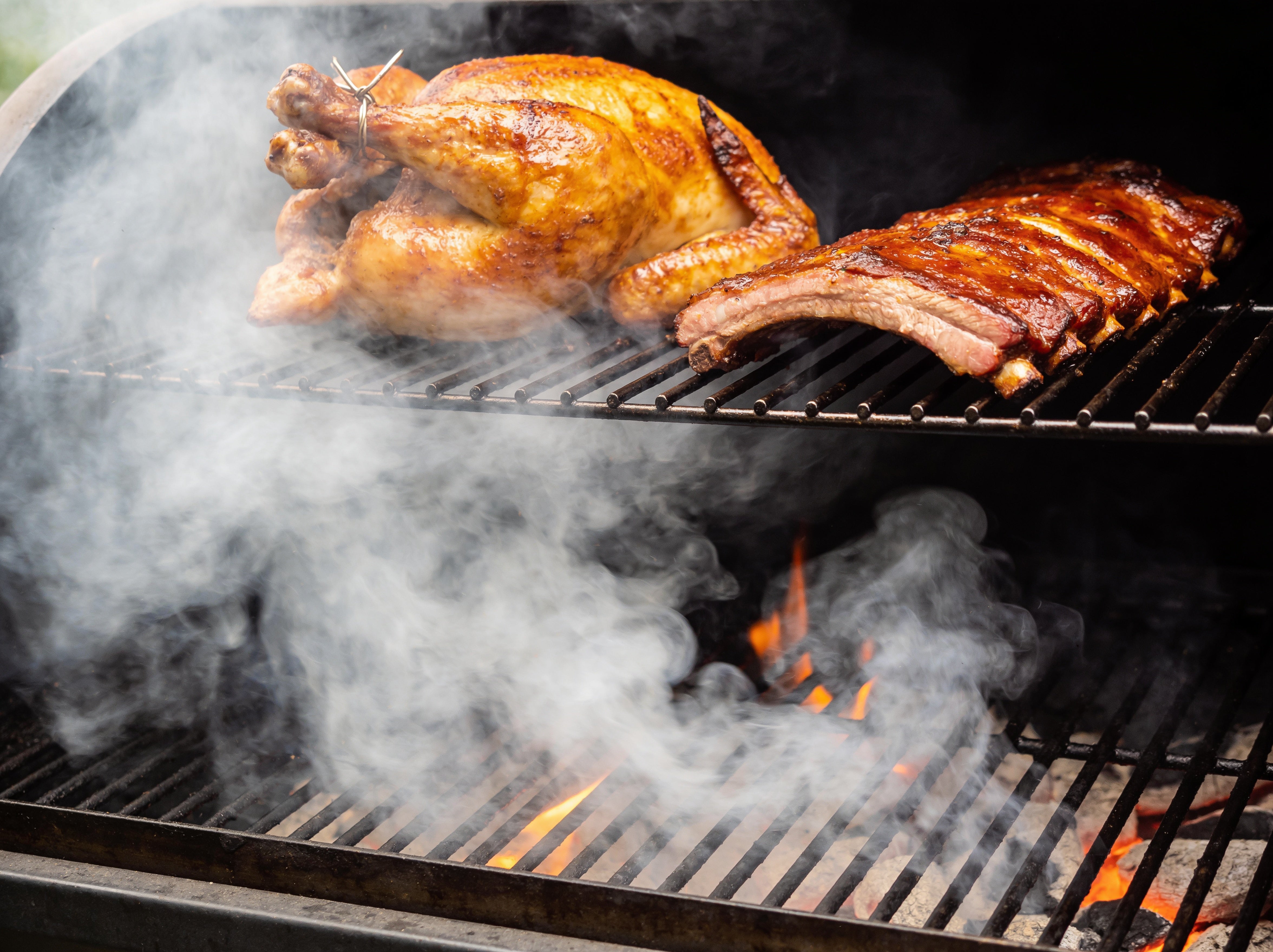 Western BBQ Products Apple Smoking Wood Chips lifestyle photo — roast chicken and pork ribs smoking over apple wood on the grill