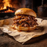Pulled pork sandwich on a brioche bun with glossy amber sauce dripping down the side