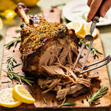 Slow-roasted lamb shoulder with golden herby crust on a wooden carving board with rosemary and lemon