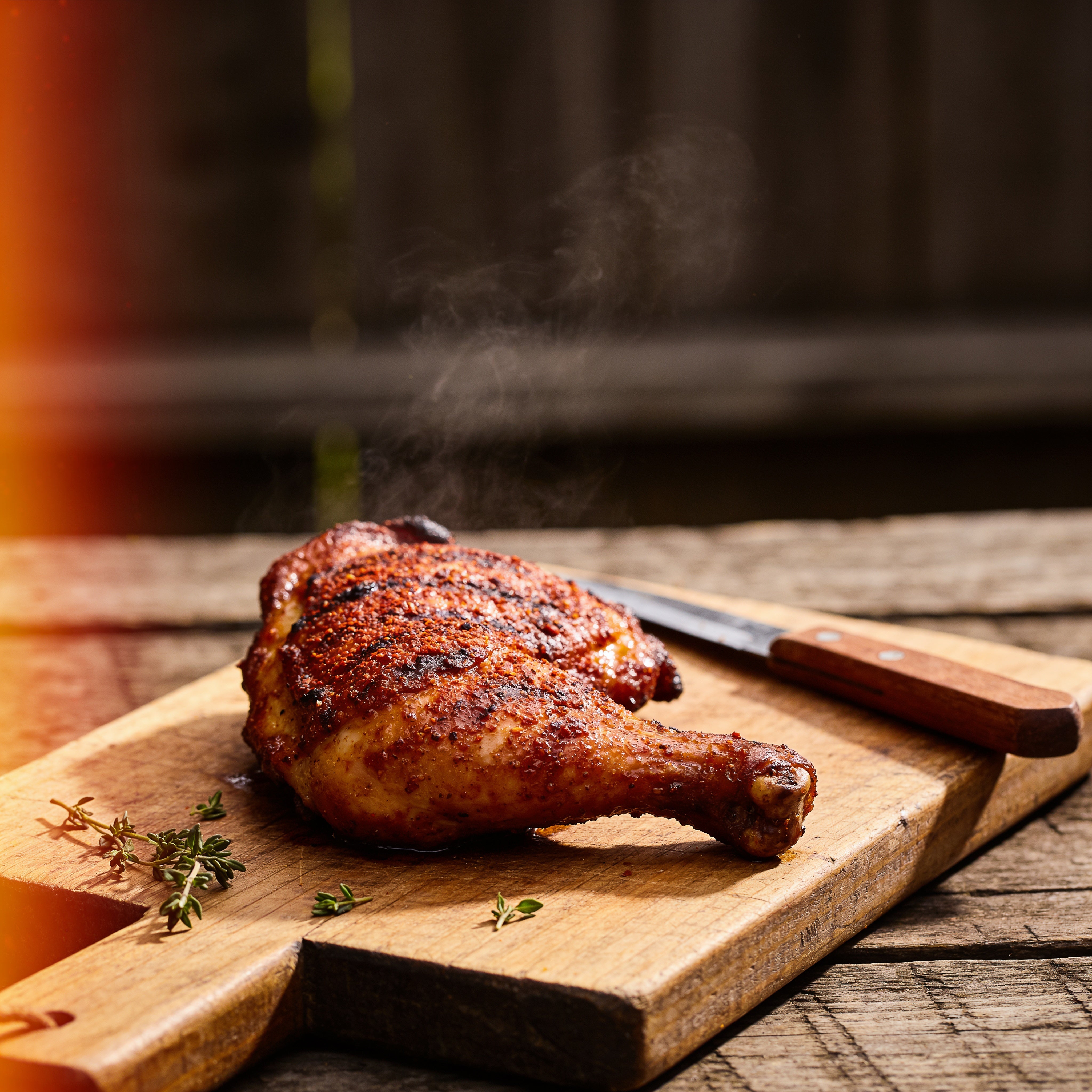 Grilled chicken thighs with a deep red-brown spice crust resting on a wooden board