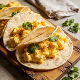 Breakfast tacos with scrambled eggs and coriander garnish on a wooden board