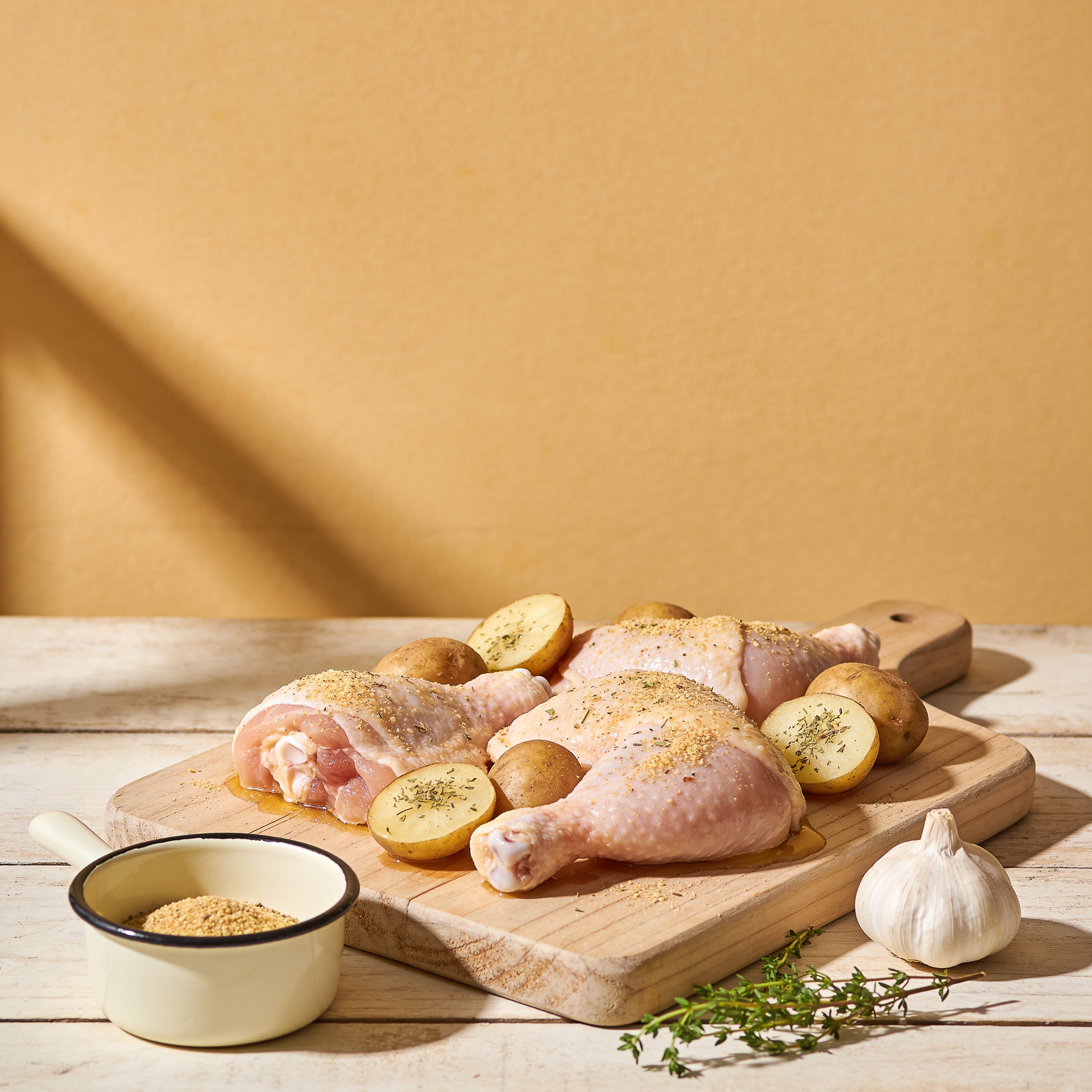 Outlaw Barbecue Gold Rush 280g garlic butter BBQ rub — raw chicken and baby potatoes seasoned and ready to cook