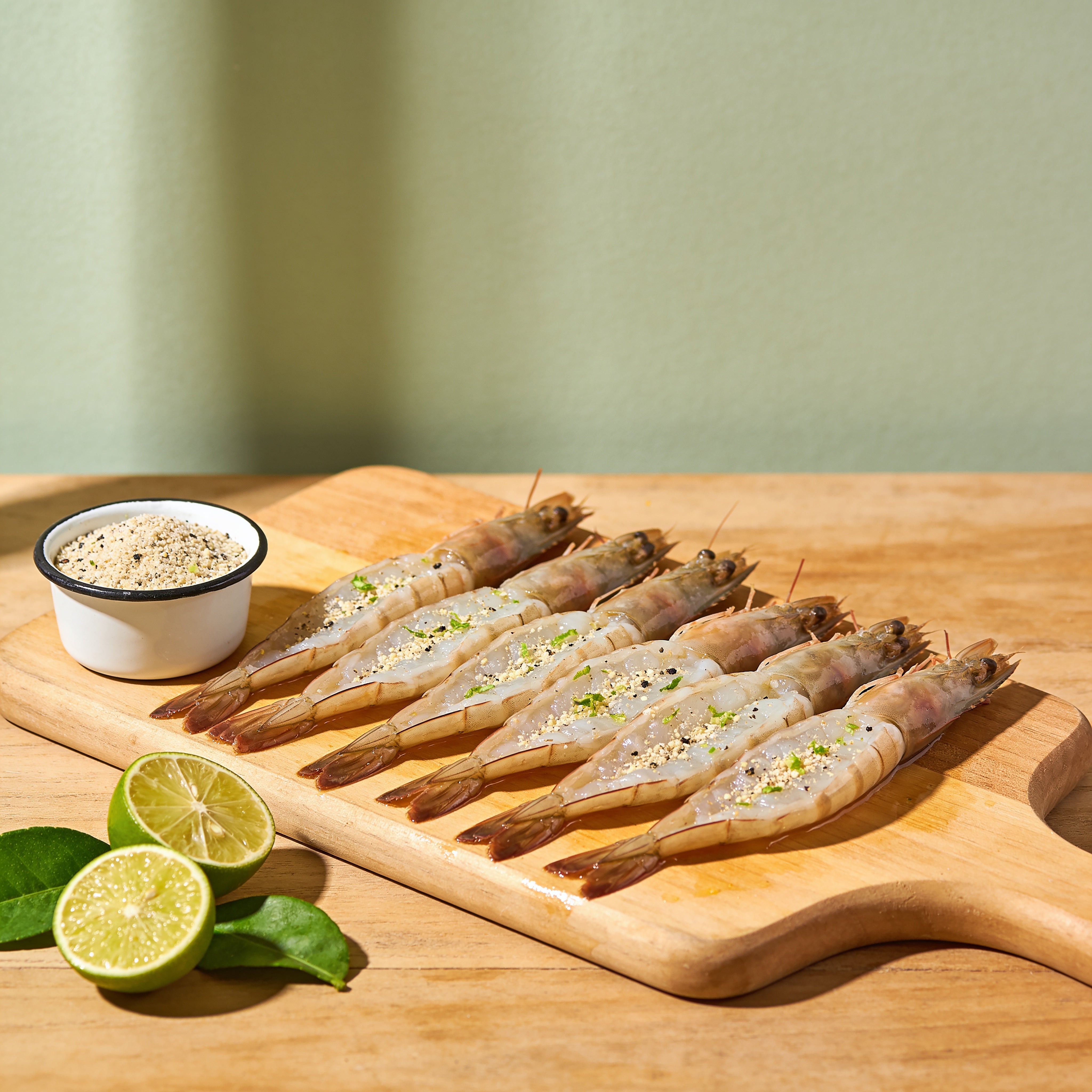 Outlaw Barbecue Lawless 220g lime and black pepper BBQ rub — raw king prawns seasoned and ready to cook with limes