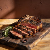 Outlaw Barbecue Stockman CRUST 250g espresso beef rub — sliced T-bone with a dark coffee-pepper crust on a timber board
