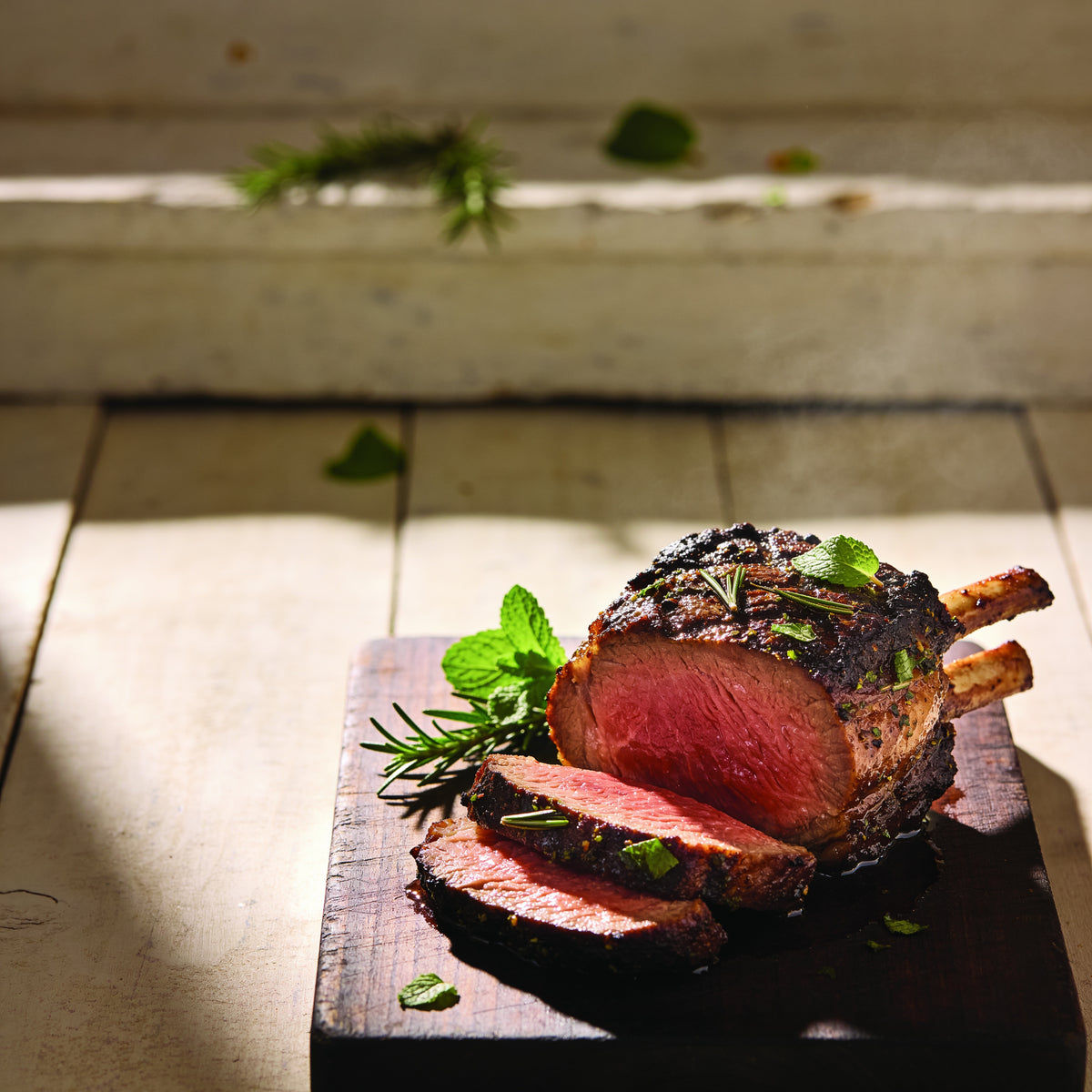 Cut-face macro of a grilled lamb cutlet with mint and rosemary