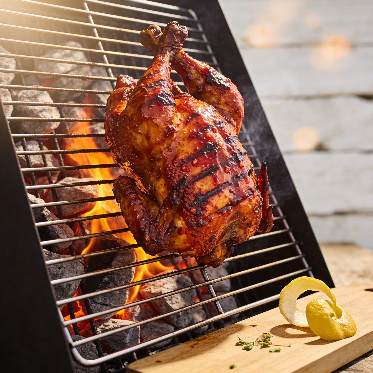 Low-angle whole butterflied chicken flame-grilled over open coals