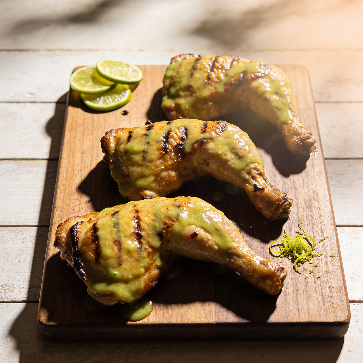 Glazed grilled chicken thighs with lime wheels and citrus sheen