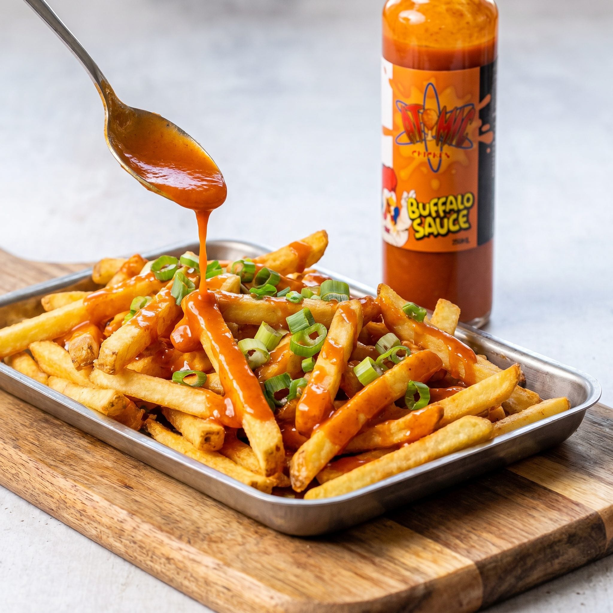 Atomic Chicken Buffalo Hot Sauce — loaded fries drizzled with buffalo sauce and spring onion