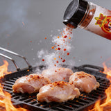 Atomic Chicken Chicken Peri Peri Seasoning Rub 200g — seasoning shaken over raw chicken thighs on a flaming grill, spice frozen mid-air