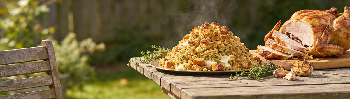 Atomic Chicken Chicken Stuffing with a generous mound of herby stuffing beside a whole roast chicken on a sunlit backyard table
