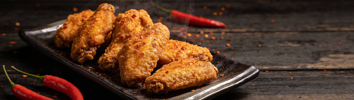 Atomic Chicken Hot 'N Spicy Southern Fried Chicken Coating with golden fried chicken flecked with red chilli beside fresh red chillies