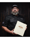 Barbecue Fusion by Adam Roberts hardback cookbook — Adam Roberts holding the book