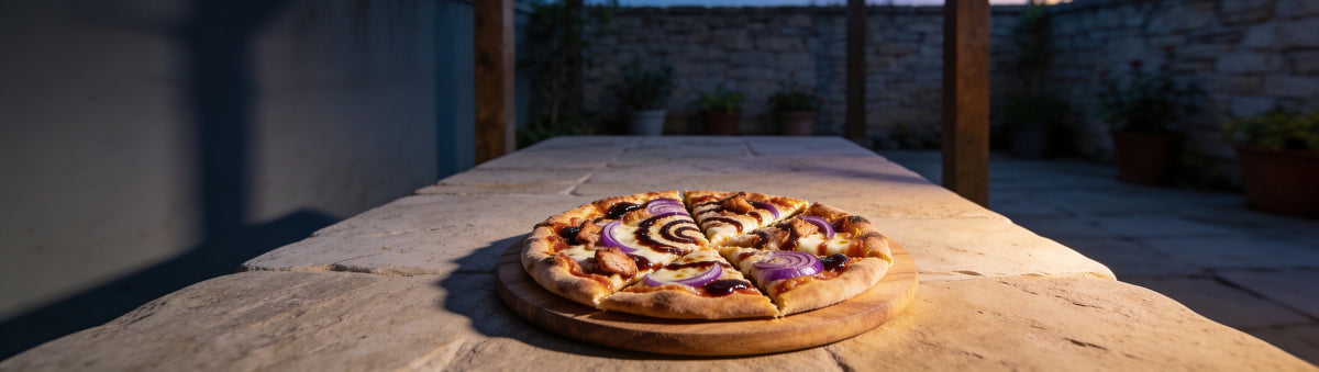 BBQ chicken pizza swirled with BBQ Mafia Mobster BBQ Sauce on a garden table at twilight
