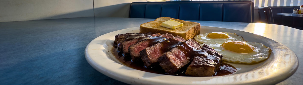 Steak and eggs breakfast with BBQ Mafia The Don Steak Sauce in a sunlit diner booth