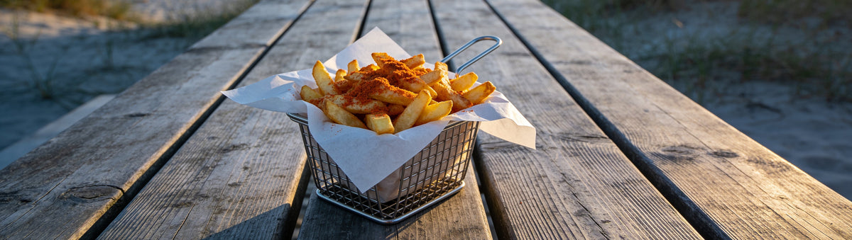 Hot chips dusted with BBQ Mafia The Oath Chip Seasoning on a beach picnic table at sunset