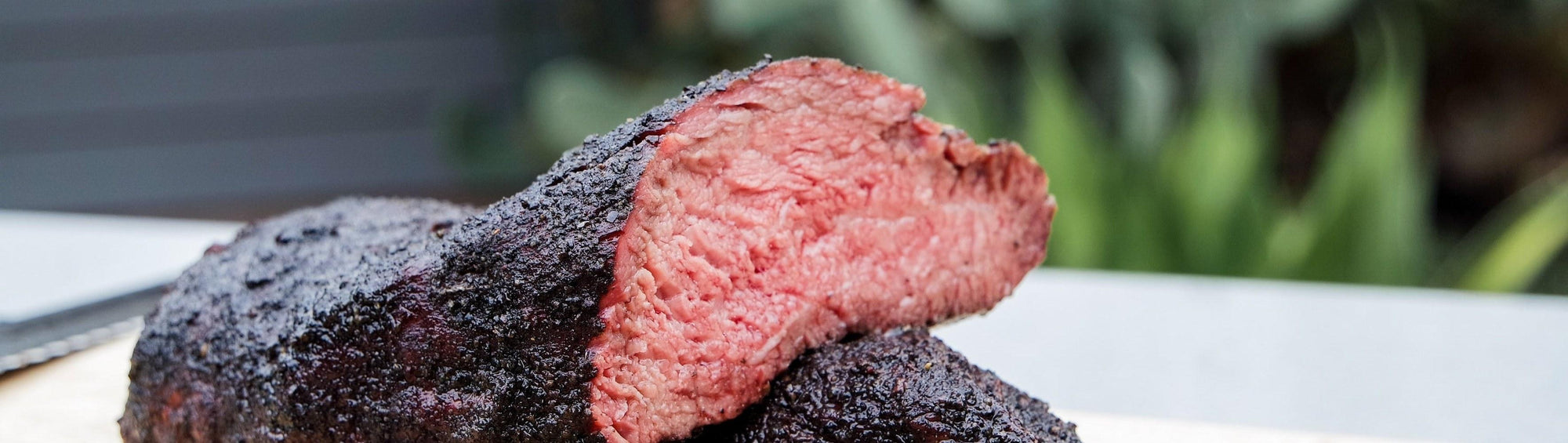 Hardcore Carnivore Black beef rub beside sliced smoked brisket with a jet-black activated-charcoal bark and pink smoke ring