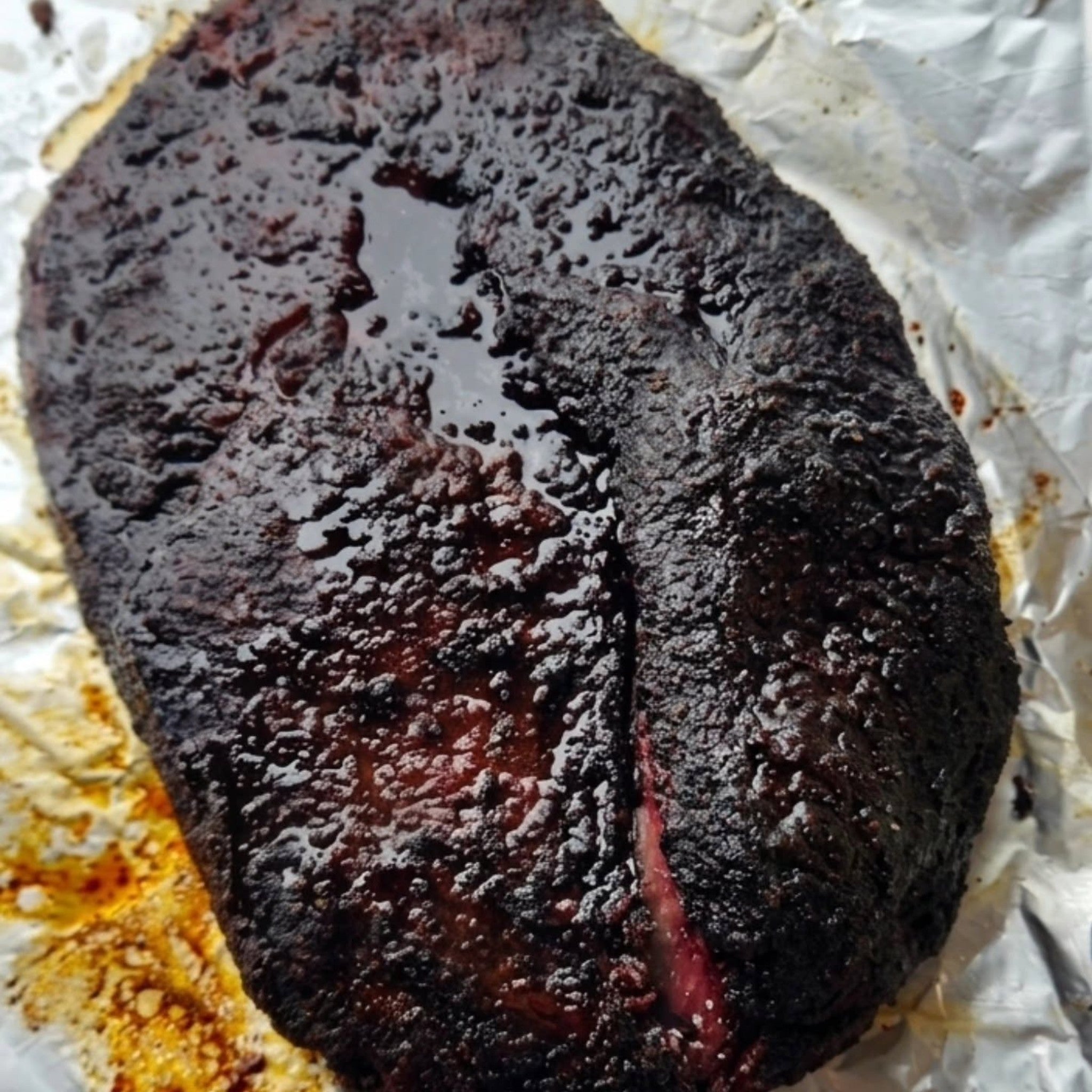 Butchers Axe Bullseye beef rub — whole smoked brisket with dark peppery bark held on foil, cooked by Butchers Axe BBQ Melbourne