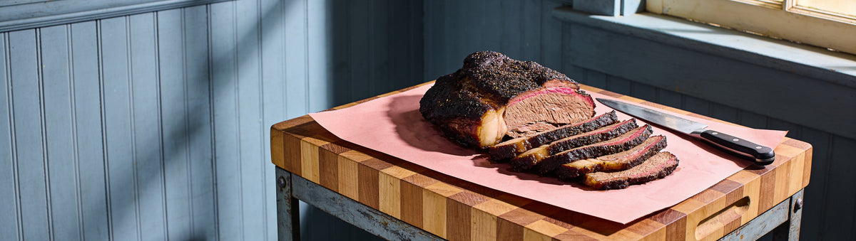 Sliced peppery-bark smoked brisket on butcher paper, seasoned with Carolina Smoke Beef Seasoning