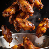 Chicken Jockey box - sticky honey mango glazed chicken wings caught mid-toss above a steel bowl
