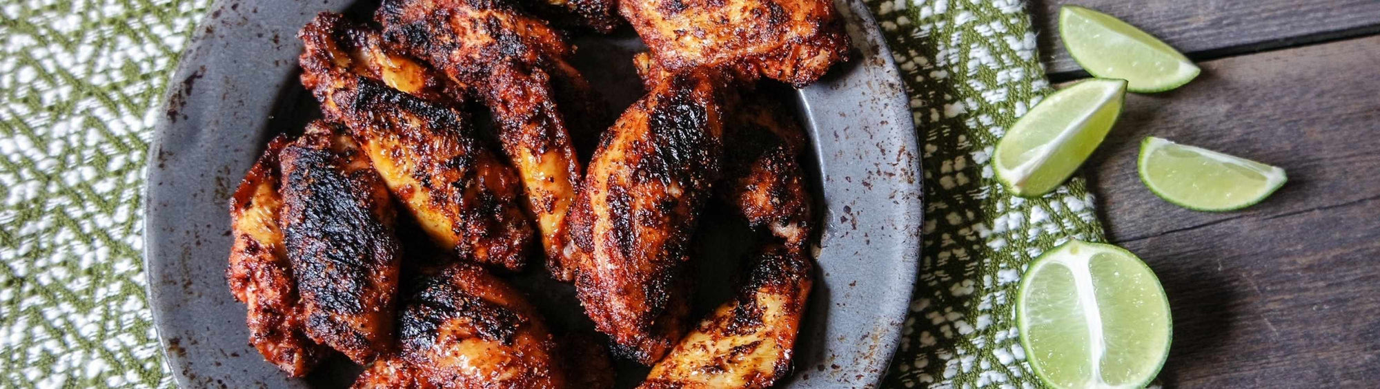 Hardcore Carnivore Chilli Lime Meatchelada rub beside charred grilled wings and street tacos with fresh lime and chilli