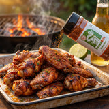 Chuds BBQ SnakeBite 280g spicy jalapeño BBQ rub — glossy barbecue wings on an enamel tray by the coals