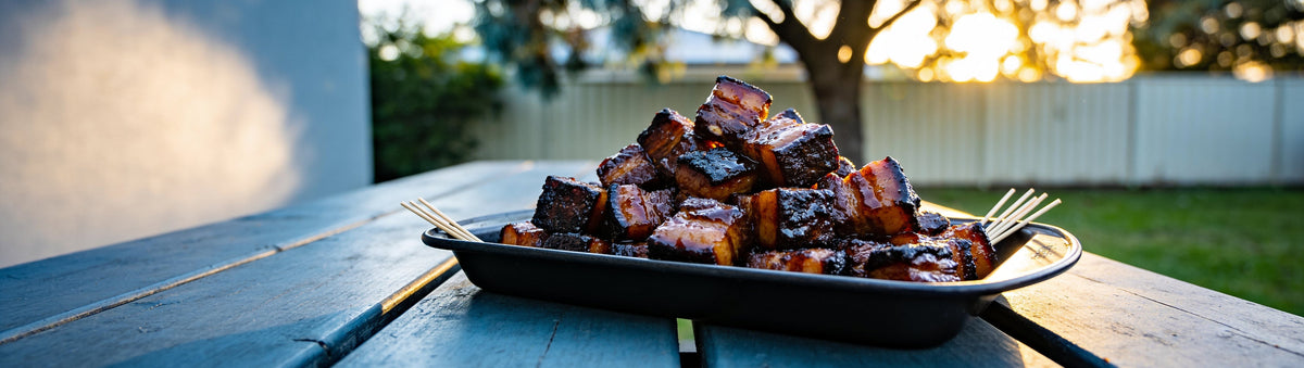 Maple-glazed pork belly burnt ends on a backyard picnic table – Chuds BBQ SweetCheeks