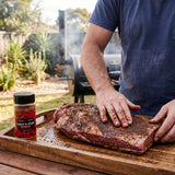 Coast n Smoke Bells Double Shot coffee rub — a pitmaster rubbing the coffee rub onto a raw beef brisket