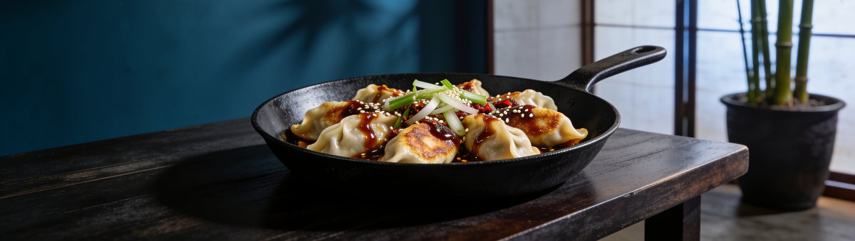 Pan-fried pork dumplings drizzled with Cobra Chilli Habanero Magic Sauce in a skillet