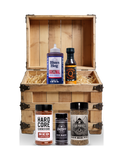 The Rub Hub The First Mate BBQ subscription box — example crate with Blues Hog Original, Kosmos Q Honey Jalapeño, Hardcore Carnivore Red, Butchers Axe Big Bark and Four Monkeys Home Base — contents change monthly, on transparent background
