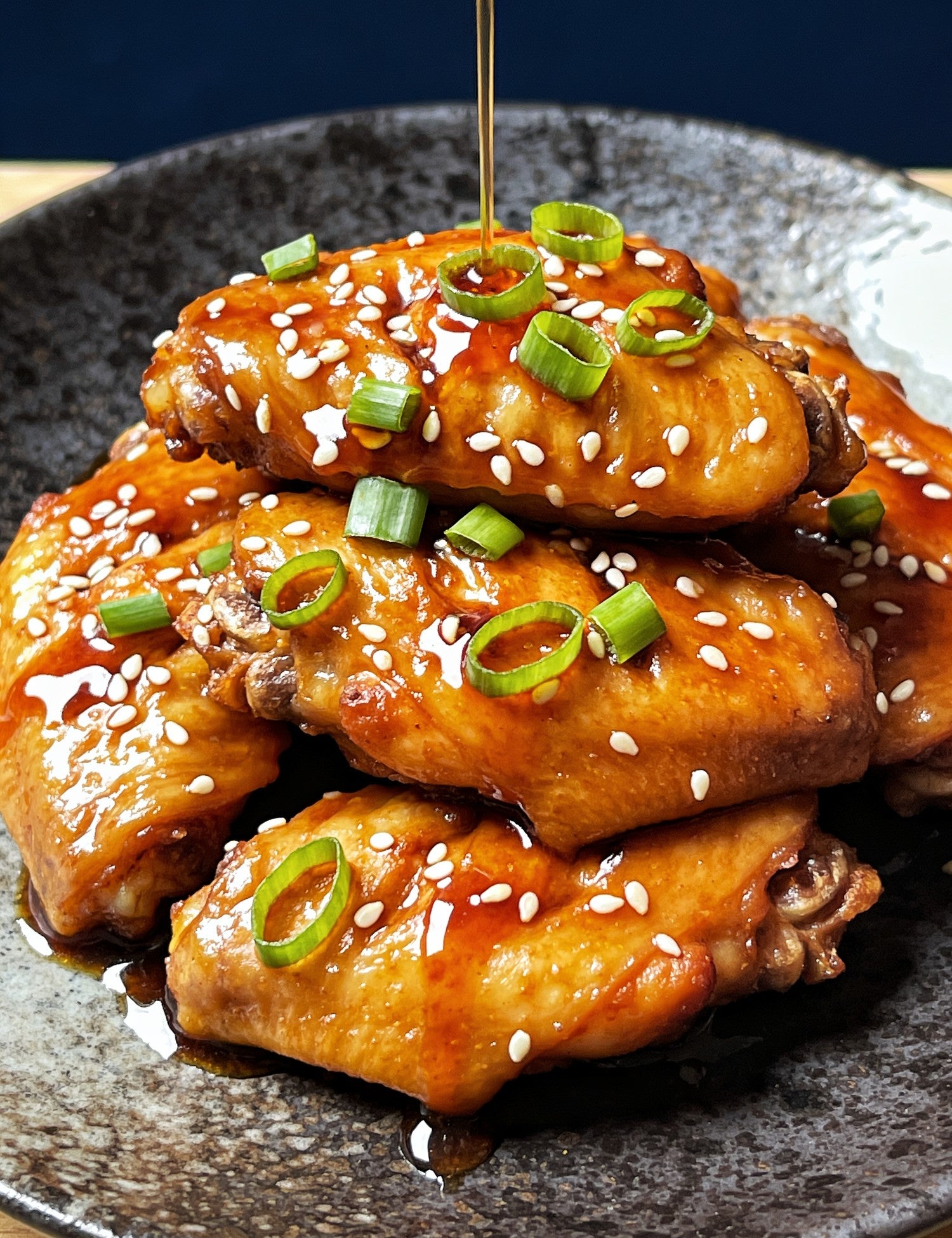 The Smuggler's Gift Crate lifestyle — close-up of glazed chicken wings with sesame and spring onion