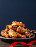 The Smuggler's Gift Crate lifestyle — platter of sticky glazed chicken wings with a red ribbon