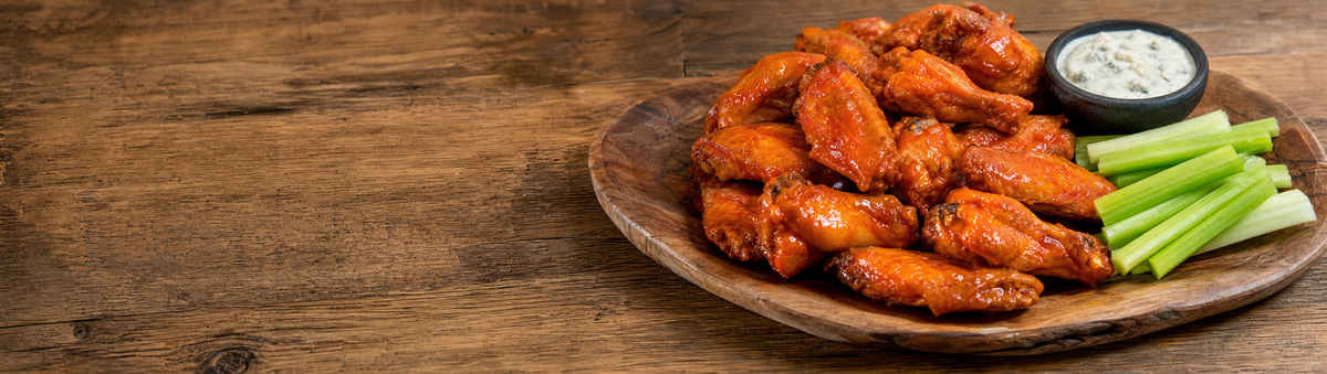 Buffalo-glazed chicken wings with celery and blue cheese on a platter