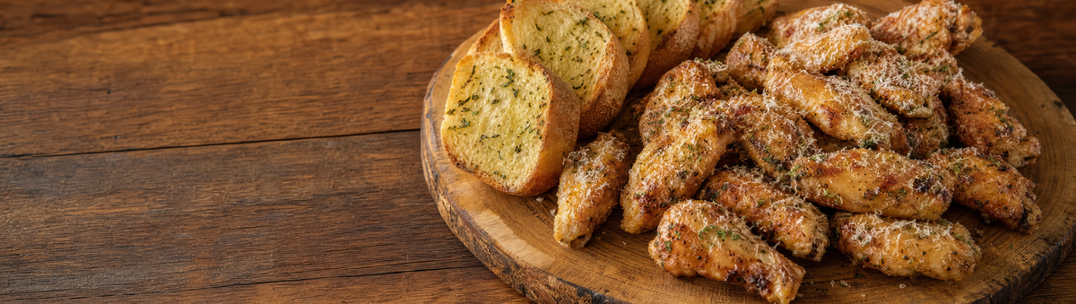 Parmesan garlic chicken wings and garlic bread on a rustic wood platter