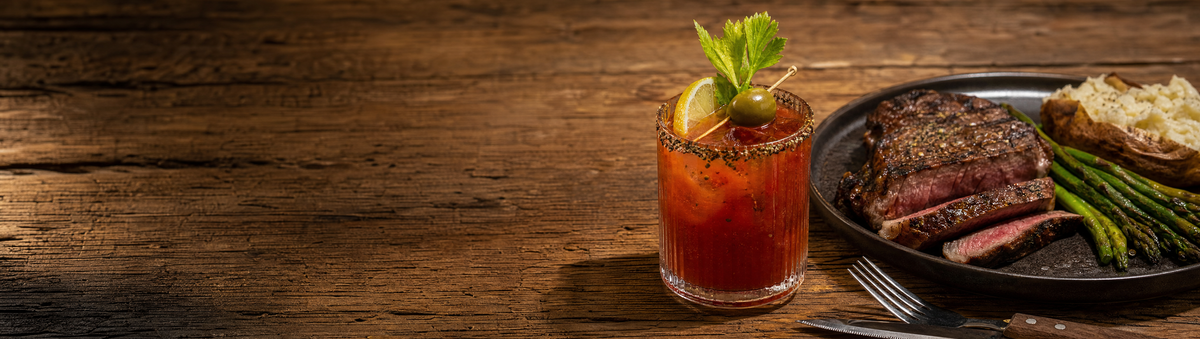 A cracked-pepper Bloody Mary cocktail on a steak-night dinner table