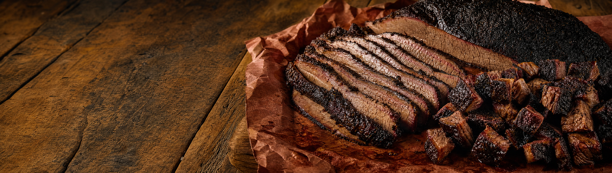 Sliced brisket and burnt ends resting on butcher paper on a rustic table