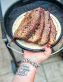 Diva Q's Barbecue by Danielle Bennett paperback cookbook — sliced smoked brisket held over the grill