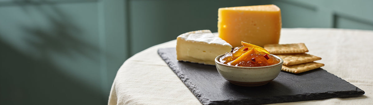 Cheese board with brie, cheddar and Flavour & Spice Chilli Chai Jam on slate