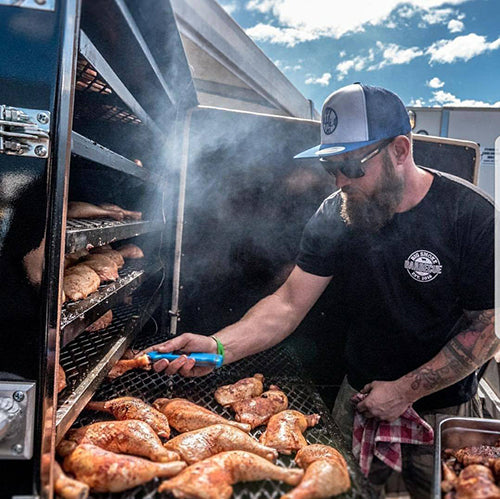 Daniel Barrett, Four Monkeys BBQ founder and 2017 Australian BBQ Champion, loading chicken quarters onto a competition smoker lifestyle photo