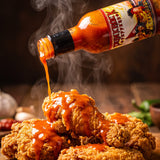 Happy Cayanero cayenne hot sauce drizzled over fried chicken
