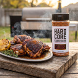 Hardcore Carnivore Cajun Rub — blackened Cajun chicken thighs on a board beside the shaker