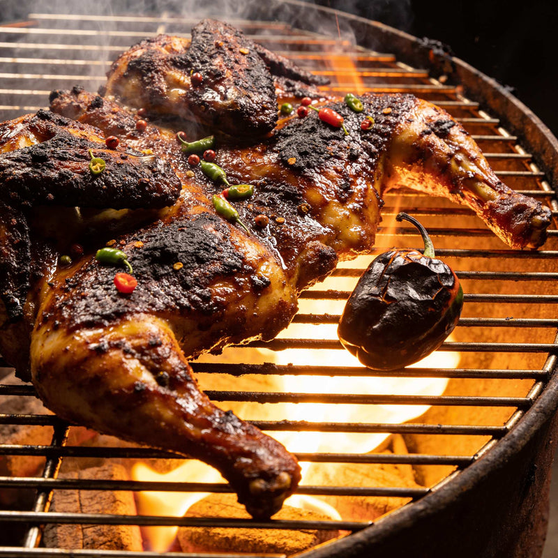 Authentic Jamaican jerk chicken with a near-black bark and scotch bonnet char on the grill — Jamaican flavour on The Rub Hub lifestyle photo