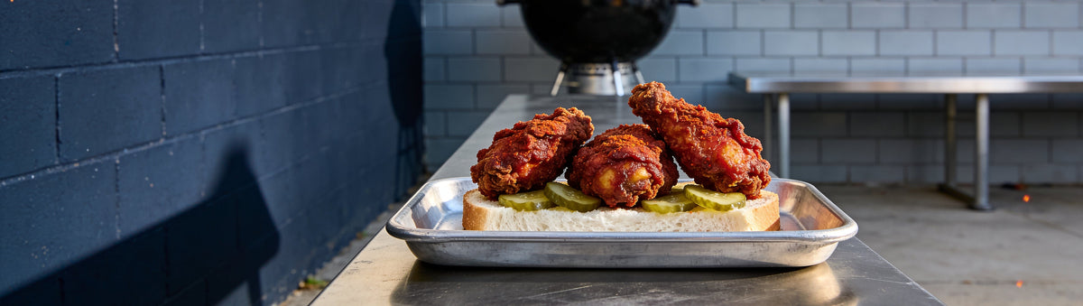 Nashville hot fried chicken with pickles on white bread, dusted with KOSMOS Q Nashville Hot Wing Dust