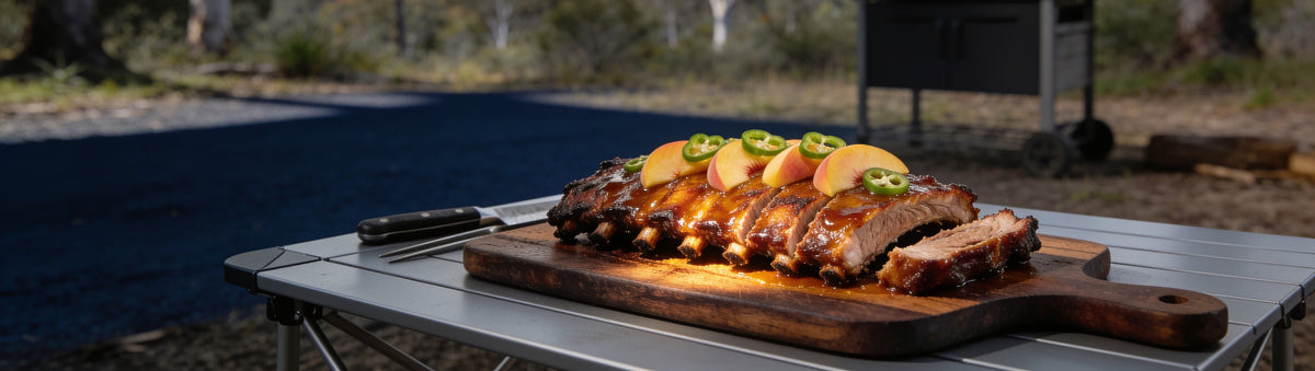 Pork ribs lacquered in KOSMOS Q Peach Jalapeno Rib Glaze on a bush camp table