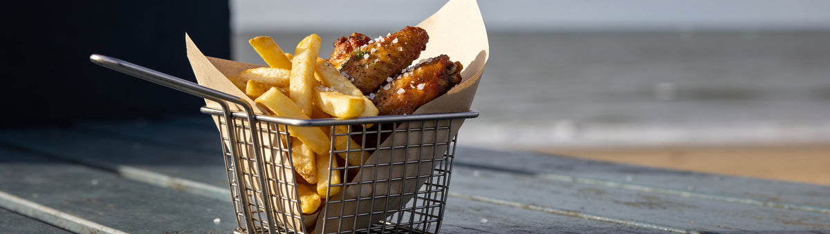 Wings and chips shaken with KOSMOS Q Salt & Vinegar Wing Dust on a seaside deck table