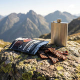 Low n Slow Basics Garlic Goals beef jerky — an open pack of beef jerky on a rock during a hiking trip