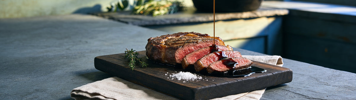 Mitch's Preserves Worcestershire Sauce: Sliced rib eye with Worcestershire sauce poured over on a dark timber board