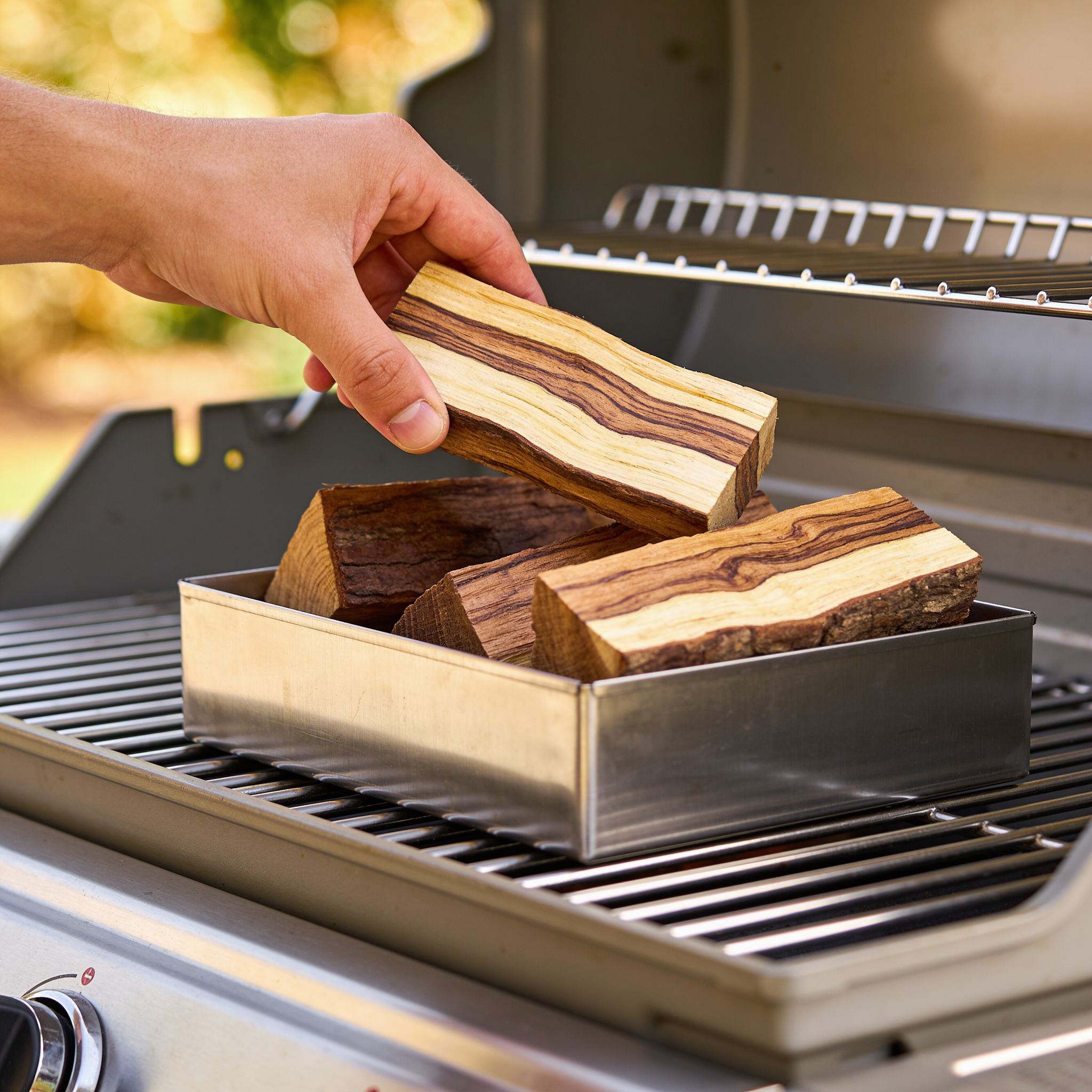 Natural Smoke Olive wood chunks being added to a smoker box on the BBQ