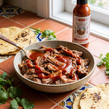 Nomad Chilli Co Habanero Roja hot sauce — slow-cooked pulled pork in a bowl with habanero sauce swirled through