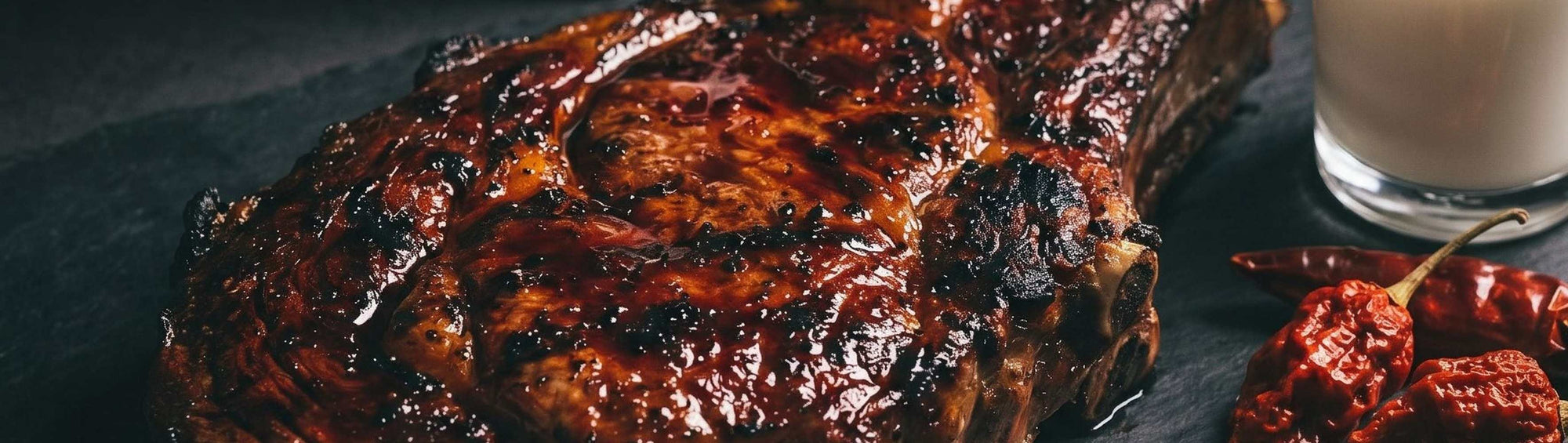 Nomad Chilli Co Reaper Roja Hot Sauce spooned over grilled steak with charred jalapeño, fermented hot sauce
